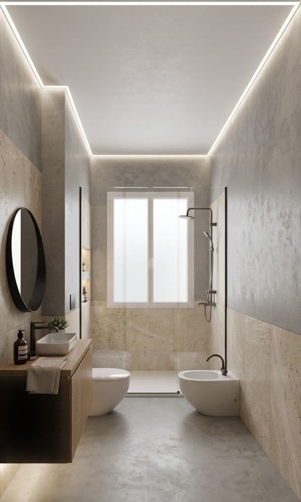 Casa C, Bologna: bagno stretto e lungo con rivestimenti in travertino, effetto resina e illuminazione perimetrale a LED