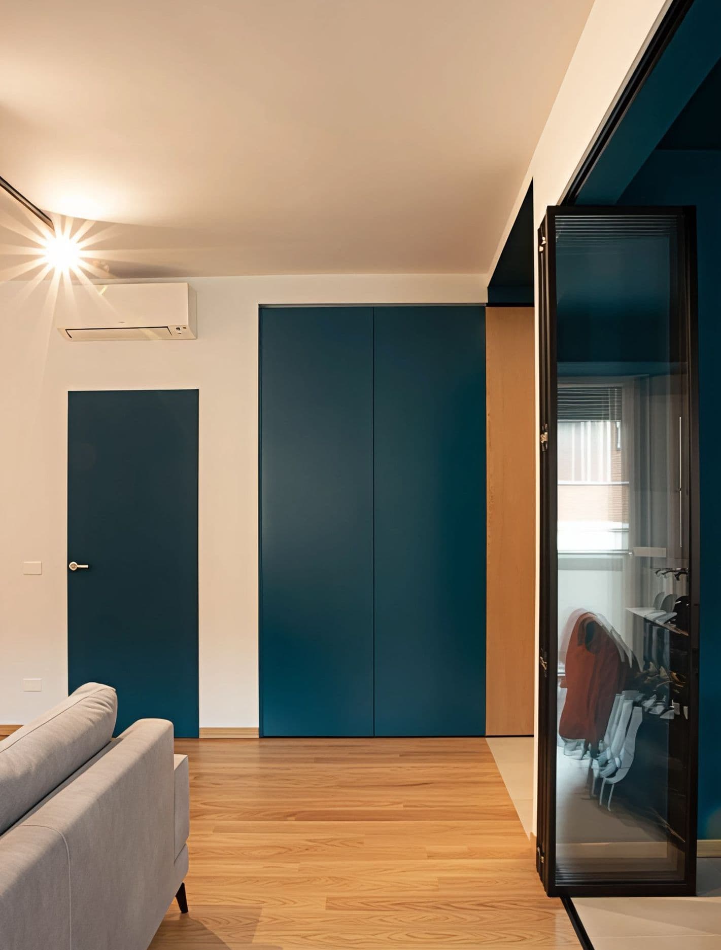 Casa Vito, Ferrara: zona giorno con porte a tutta altezza blu ottanio e parquet in rovere